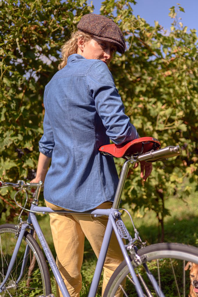 Elegante fotografo professionista Giorgio Zanetti durante uno shooting naturale con bici, ambientato in un suggestivo giardino verde con foliage autunnale, perfetto per servizi fotografici di alta qualità.